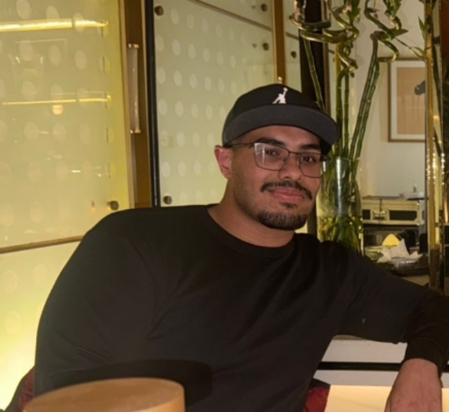 Adam Mahfouz wearing a black cap and glasses